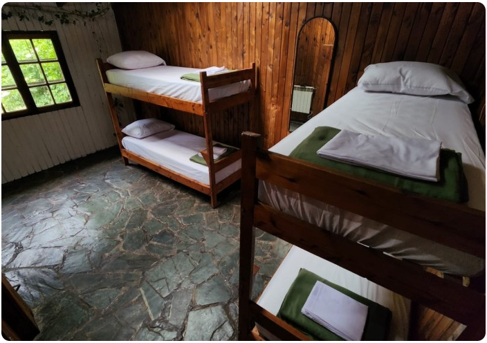 Habitación de 4 camas con piso de piedra laja y vista al bosque