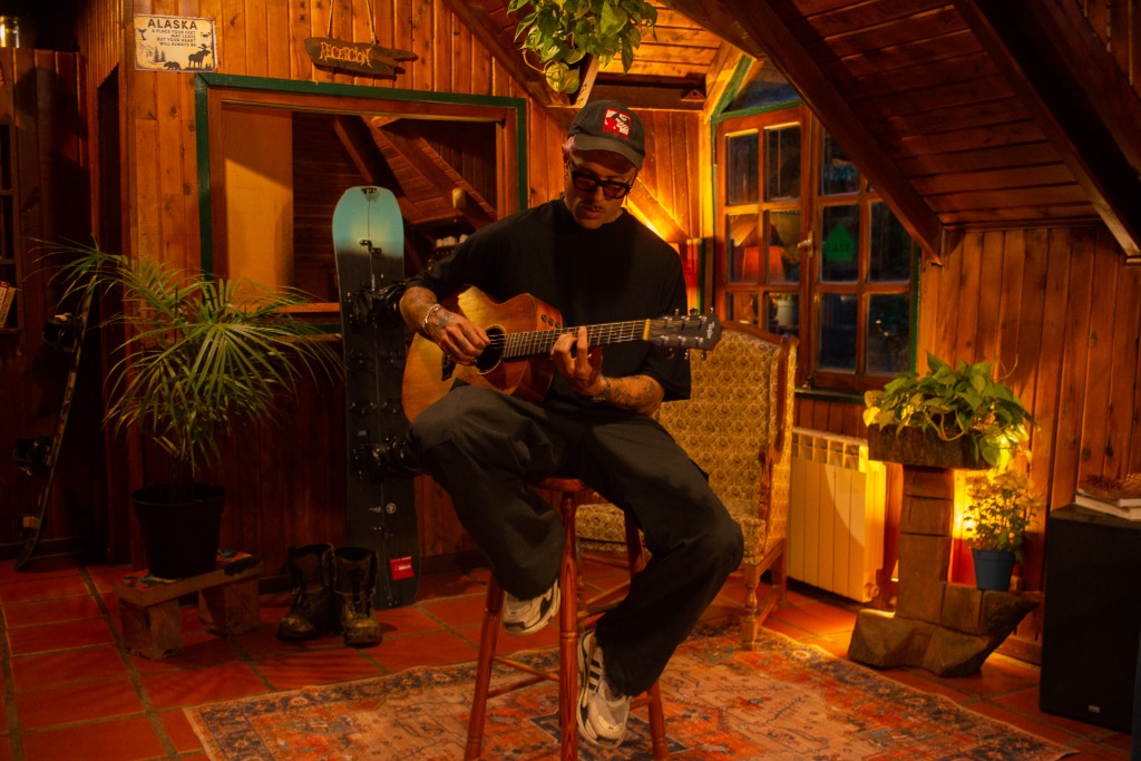 Huésped tocando guitarra en el espacio común de madera del hostel